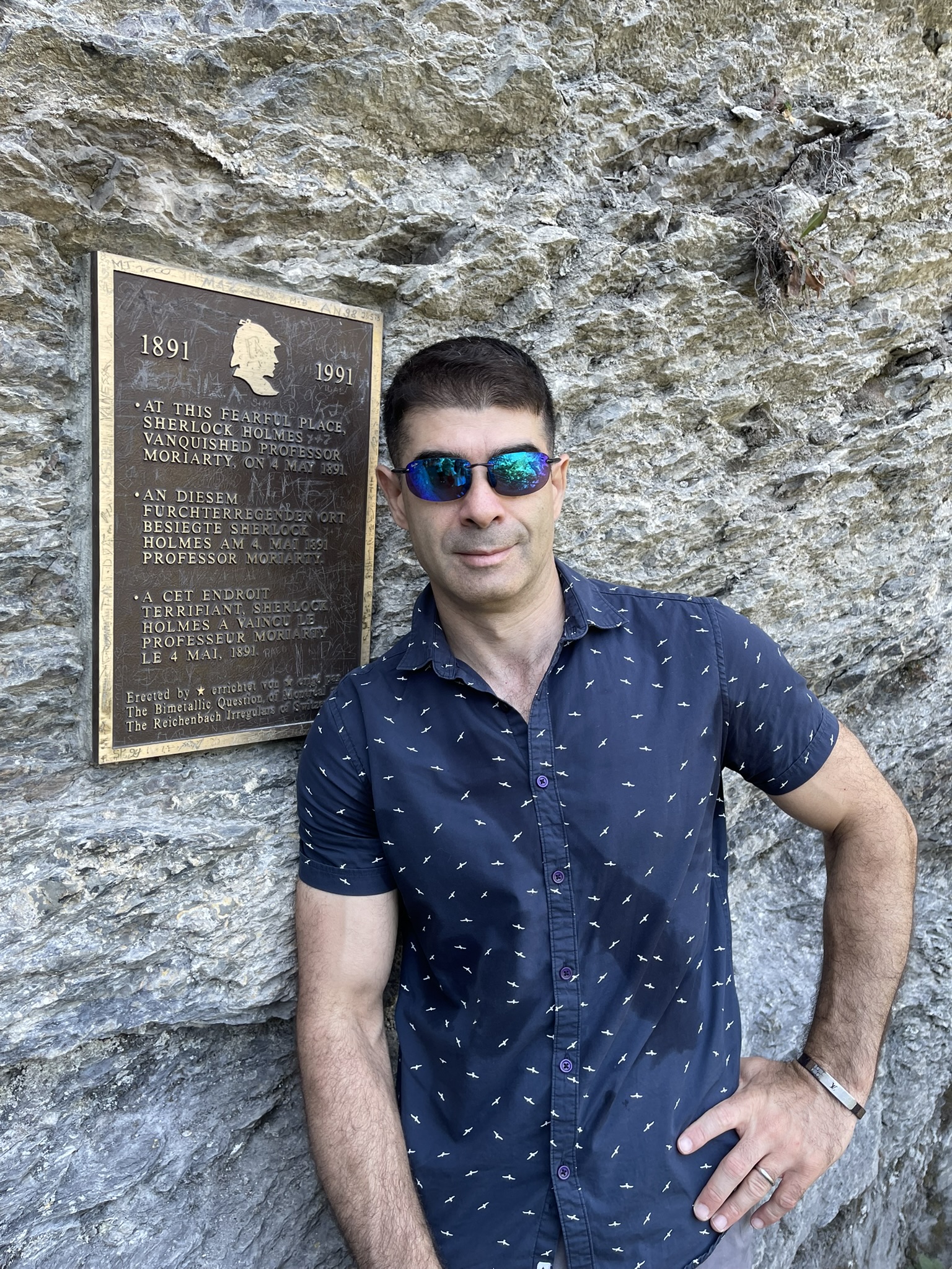 Aleksandr Mazo beside the Sherlock Holmes and Professor Moriarty memorial plaque at Reichenbach Falls in Meiringen, Switzerland.